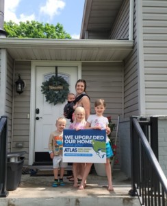 Family standing in front of their house with an Atlas Home Energy Solutions sign