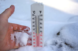 Hand holding a thermometer in the snow