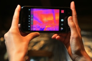 Hands holding an infrared camera up to a ceiling