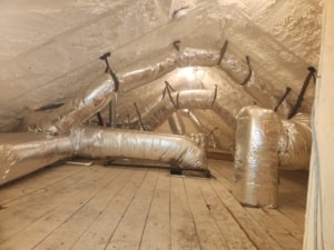 An attic with many ducts and spray foam insualtion in the walls